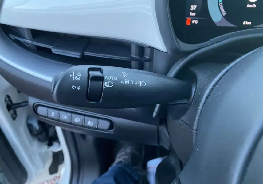 Le levier de commande des phares et clignotants dans l'habitacle d'une Fiat 500 électrique blanche, vue côté conducteur.