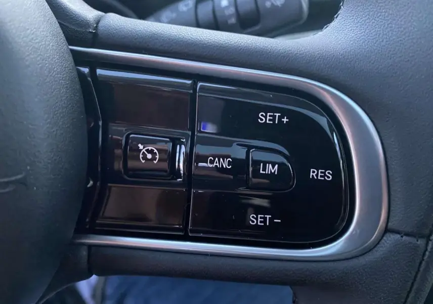 Gros plan sur les commandes du régulateur de vitesse à droite du volant de la Fiat 500 électrique blanche.