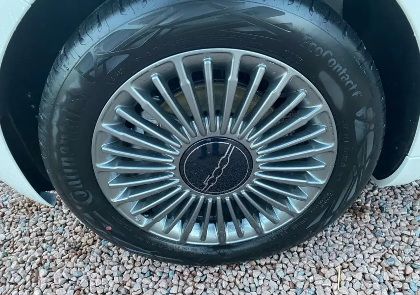 Gros plan sur la jante alliage 16'' Icône argentée d'une FIAT 500 électrique blanche, vue côté roue avant.