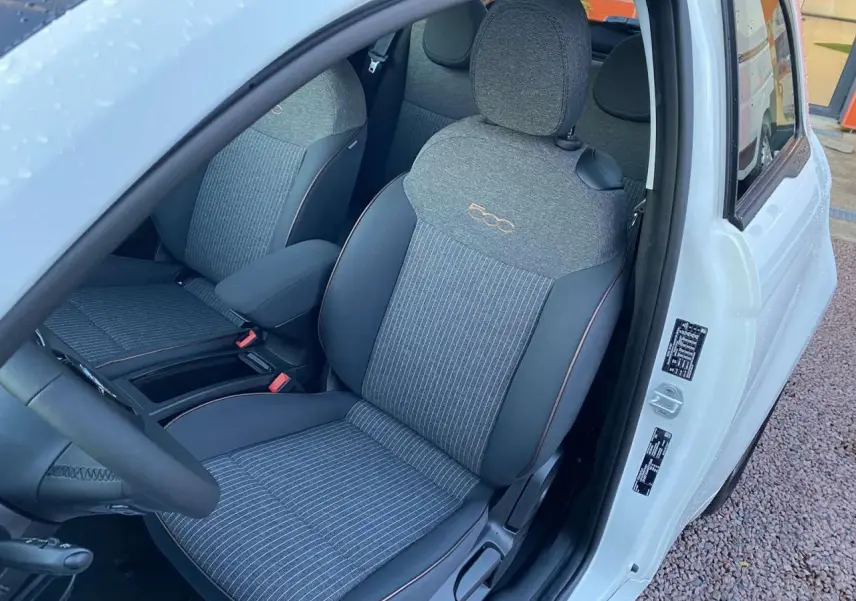Vue intérieure côté conducteur du siège avant gris avec logo 500 brodé sur une FIAT 500 électrique blanche 2022.