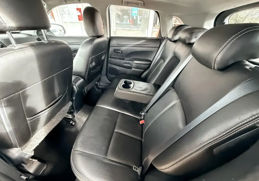 Vue intérieure arrière montrant les sièges en cuir noir avec accoudoir central et porte-gobelets du Mitsubishi ASX.