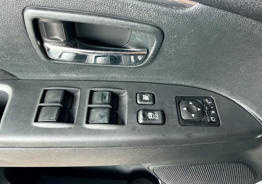 Gros plan sur la commande de lève-vitres et rétroviseurs côté conducteur du Mitsubishi ASX gris de 2015.