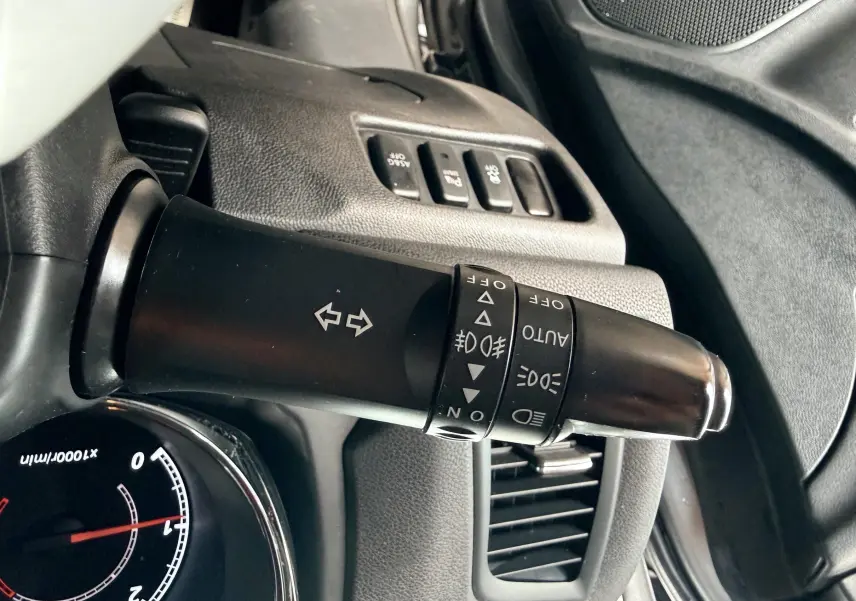 Gros plan sur la commande des clignotants et phares du tableau de bord d’un Mitsubishi ASX gris de 2015.