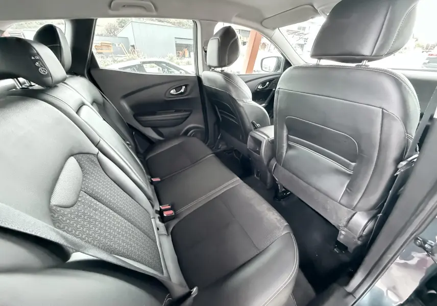 Vue intérieure arrière du Renault Kadjar 2016, sièges noirs en cuir et tissu, portes ouvertes côté droit.
