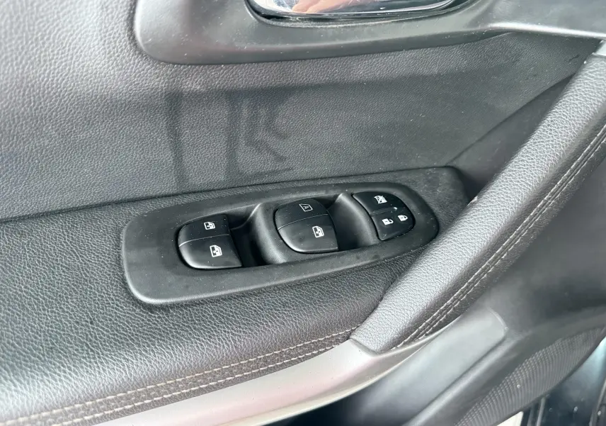 Gros plan sur les commandes de lève-vitres et verrouillage sur la porte côté conducteur du Renault Kadjar gris.