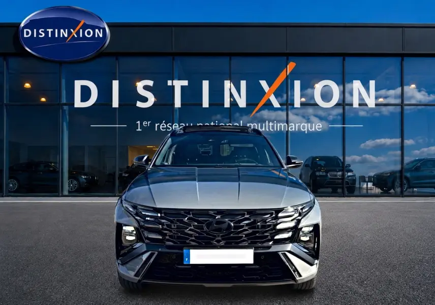 Vue avant du Hyundai Tucson gris shadow avec calandre noire et feux LED, devant une vitrine Distinxion.