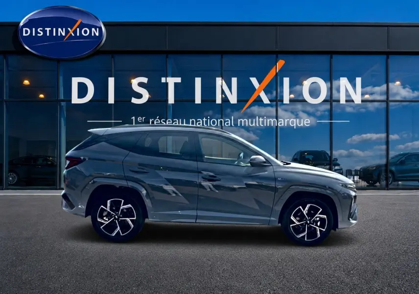Vue de profil côté gauche du Hyundai Tucson gris shadow 2026 devant une vitrine Distinxion.