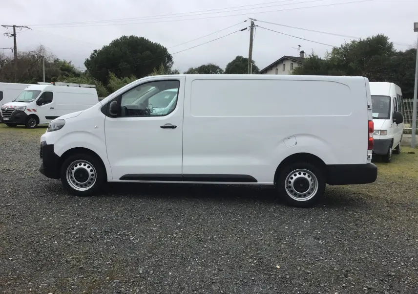 Vue de profil côté gauche d’un FIAT Scudo Fourgon blanc 2024, avec carrosserie lisse et roues acier noires.
