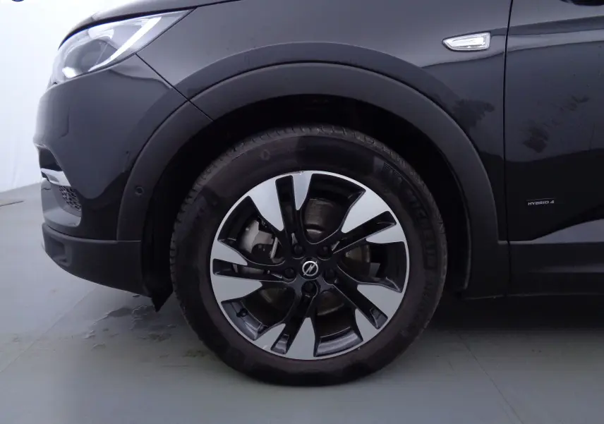 Gros plan sur la roue avant gauche noire métallisée d'un Opel Grandland X hybride avec jante alliage bicolore.
