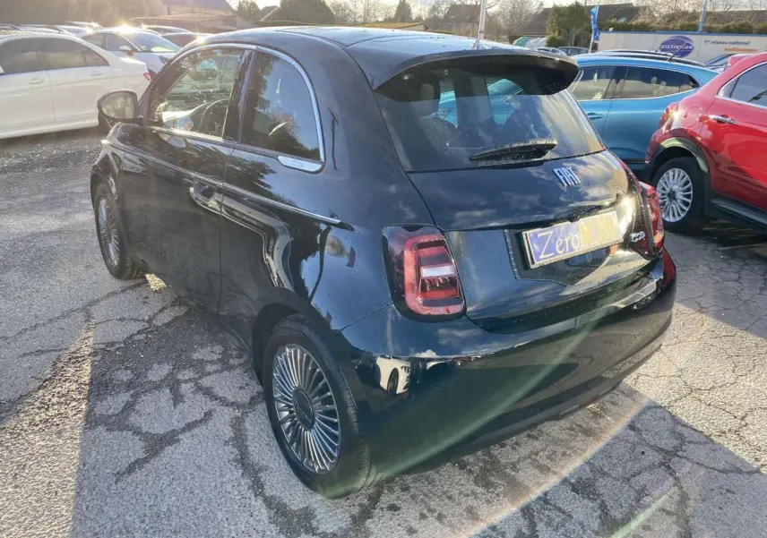 Vue 3/4 arrière droite d'une FIAT 500 électrique noire avec jantes stylisées et toit vitré panoramique.