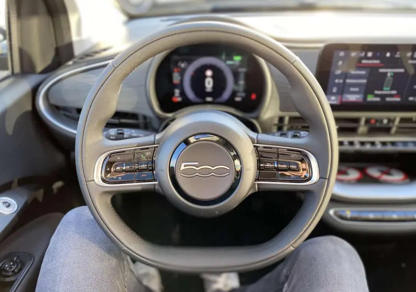 Vue centrée sur le volant noir de la FIAT 500 électrique 2022 avec tableau de bord digital et écran tactile.