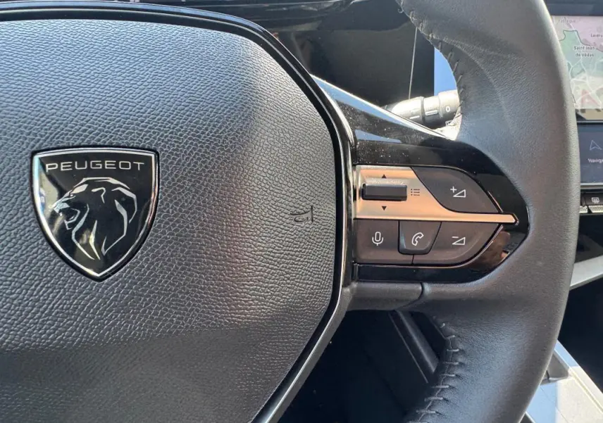 Gros plan sur le volant noir de la Peugeot 308 Hybrid 136 e-DCS6 Allure avec commandes intégrées à droite.