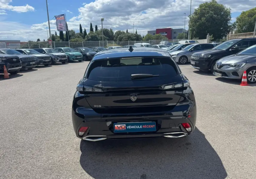 Vue arrière d'une Peugeot 308 Hybrid 136 noire, avec feux LED et double sortie d'échappement chromée visible.