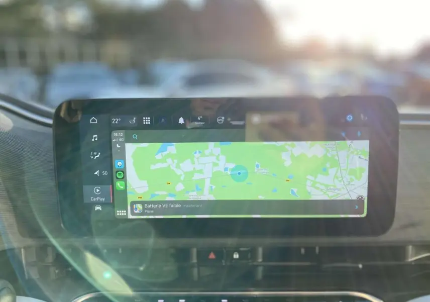 Écran tactile central affichant la navigation et l'alerte batterie faible dans l'habitacle d'une Fiat 500 électrique noire.