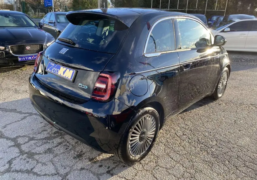 Fiat 500 électrique noire vue 3/4 arrière droit, avec jantes stylisées et poignées de portes discrètes.