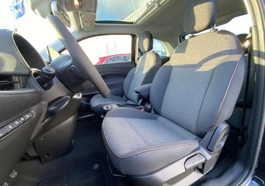 Intérieur côté conducteur de la FIAT 500 électrique noire 2022, sièges gris avec logo 500 et toit panoramique visible.