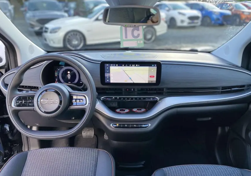 Vue intérieure avant de la FIAT 500 électrique noire 2022, tableau de bord moderne avec écran tactile et volant multifonction.