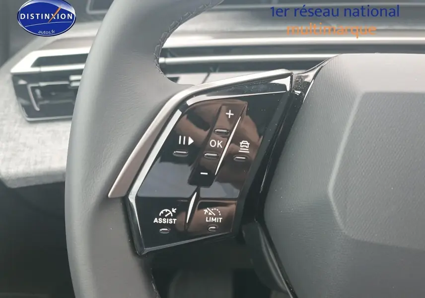 Gros plan sur les commandes multifonctions au volant côté gauche du Peugeot 5008 gris artense, intérieur moderne.