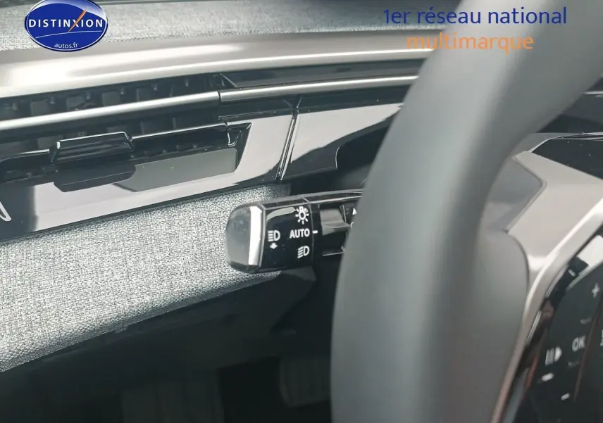 Gros plan sur la commande des phares à gauche du volant dans l’habitacle gris clair du Peugeot 5008 Hybrid 145 allure 2025.