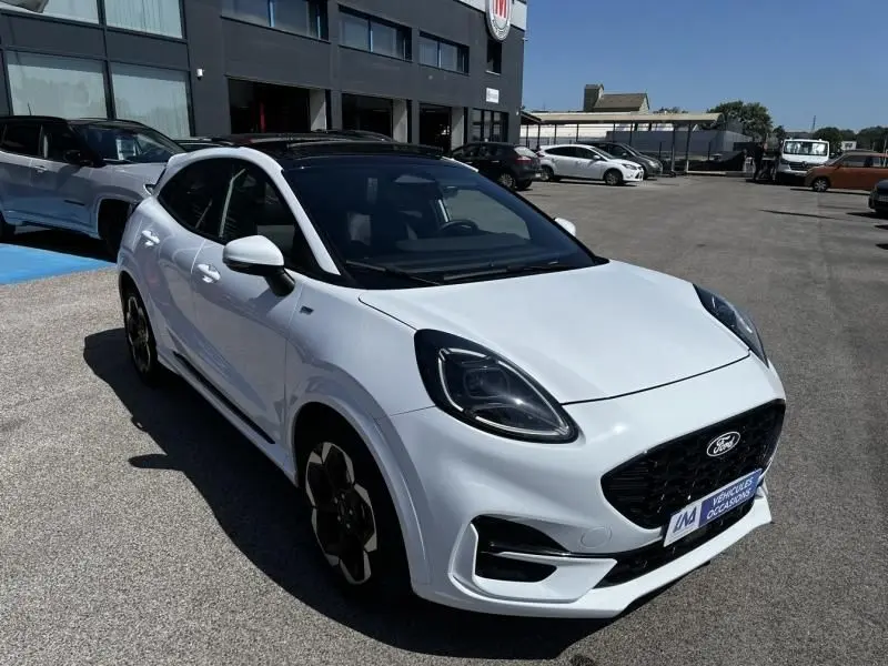Ford Puma blanc 2025 en 3/4 avant droit, toit noir, calandre noire et jantes spécifiques ST-Line X visibles.