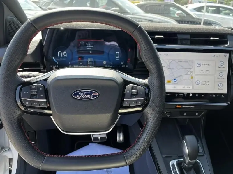 Vue intérieure centrée sur le volant Ford avec tableau de bord numérique et écran tactile du Ford Puma blanc 2025.
