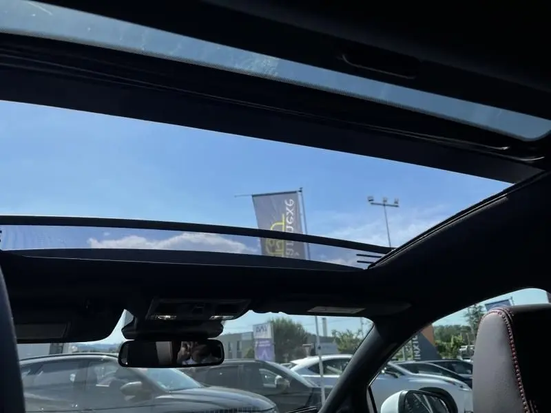 Vue intérieure du toit ouvrant panoramique du Ford Puma blanc 2025, avec ciel bleu visible à travers la vitre ouverte.
