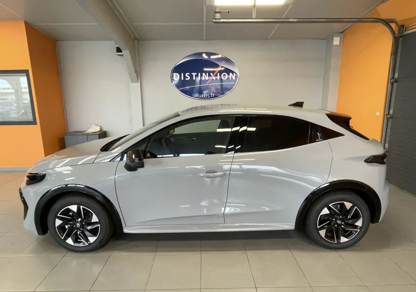 Profil droit de la Renault Clio VI TCe 115ch Techno gris Rafale métal, avec jantes noires et toit noir en showroom.