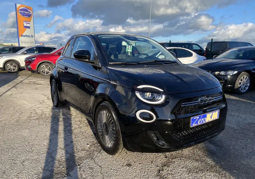 Fiat 500 électrique noire vue 3/4 avant droit, avec jantes stylisées et toit vitré panoramique visible.