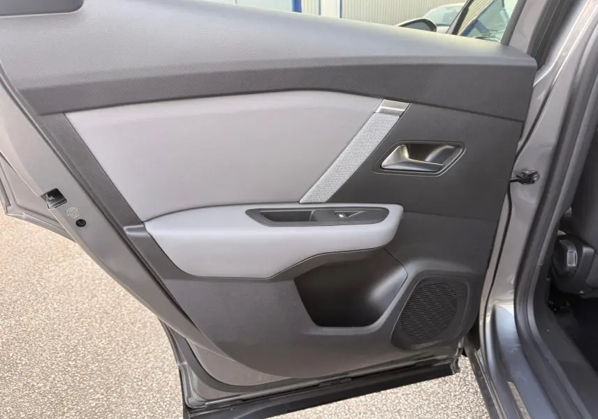 Vue intérieure sur la porte arrière droite gris Mercury du Citroën C4 hybride 2025 avec habillage bicolore et haut-parleur intégré.