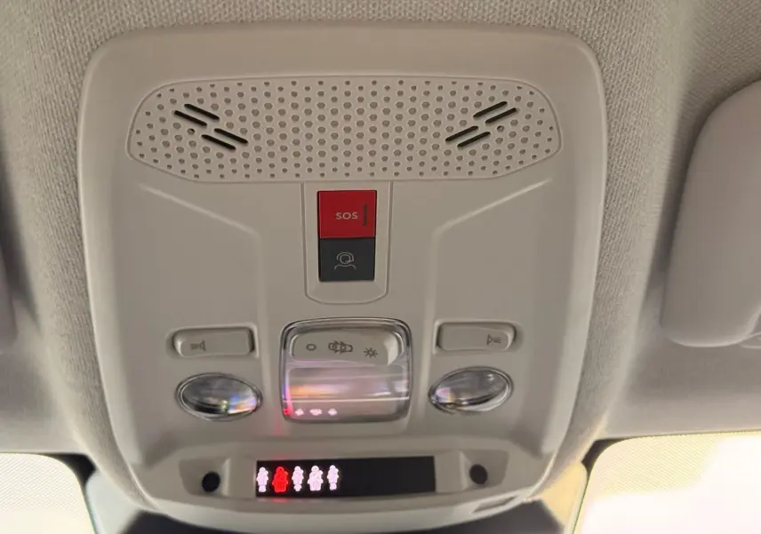 Vue en gros plan du panneau de commandes au plafond intérieur du Citroën C4 gris Mercury, avec bouton SOS rouge et éclairage intégré.