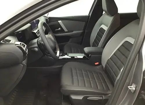 Vue intérieure côté conducteur du Citroën C4 hybride gris Mercury 2025, avec tableau de bord numérique et console centrale moderne.