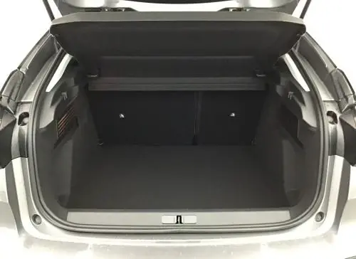 Vue intérieure du coffre spacieux et propre de la Citroën C4 hybride 2025, avec éclairage latéral et revêtement noir.