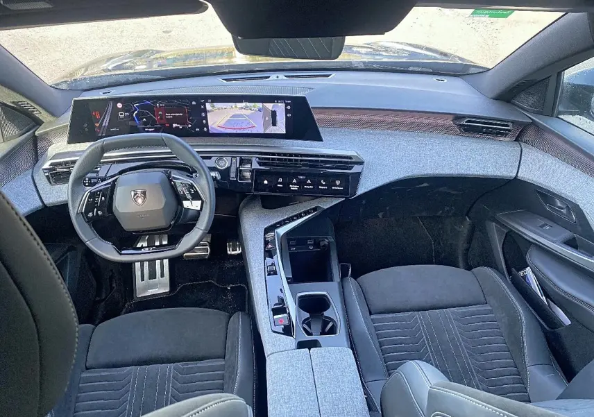 Vue intérieure avant du Peugeot 5008 Hybrid 145 GT e-dcs6 2025, tableau de bord moderne avec écran large et sièges noirs.