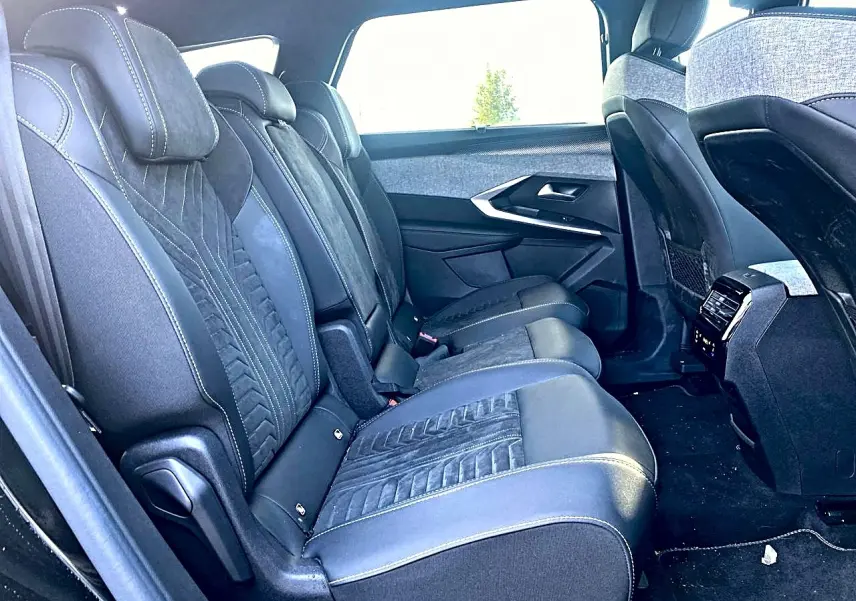 Vue latérale droite de l'intérieur arrière du Peugeot 5008 Hybrid 145 GT avec sièges en cuir noir et tissu gris.