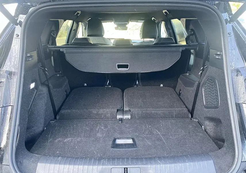 Coffre ouvert du Peugeot 5008 noir, vue arrière montrant banquette rabattue et cache-bagages en place.