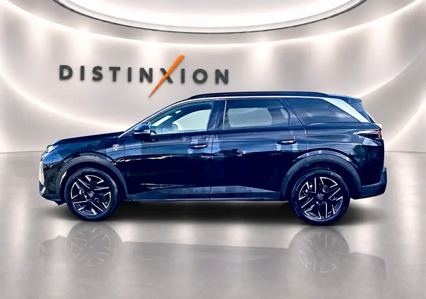 Peugeot 5008 Hybrid 145 GT noir, vue profil droit en intérieur avec jantes alliage et logo Distinxion en arrière-plan.