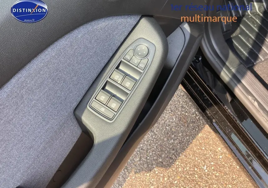 Gros plan sur la commande des vitres côté conducteur de la Renault Clio V noire Étoile, avec tissu gris et plastique noir.