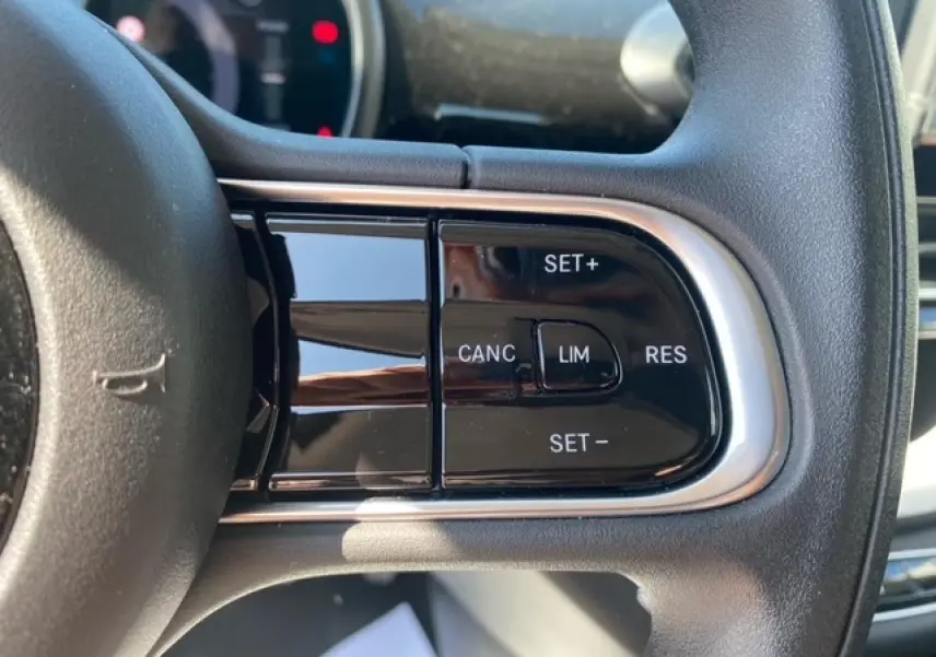 Gros plan sur les commandes de régulateur de vitesse au volant noir de la Fiat 500 électrique blanche de 2022.