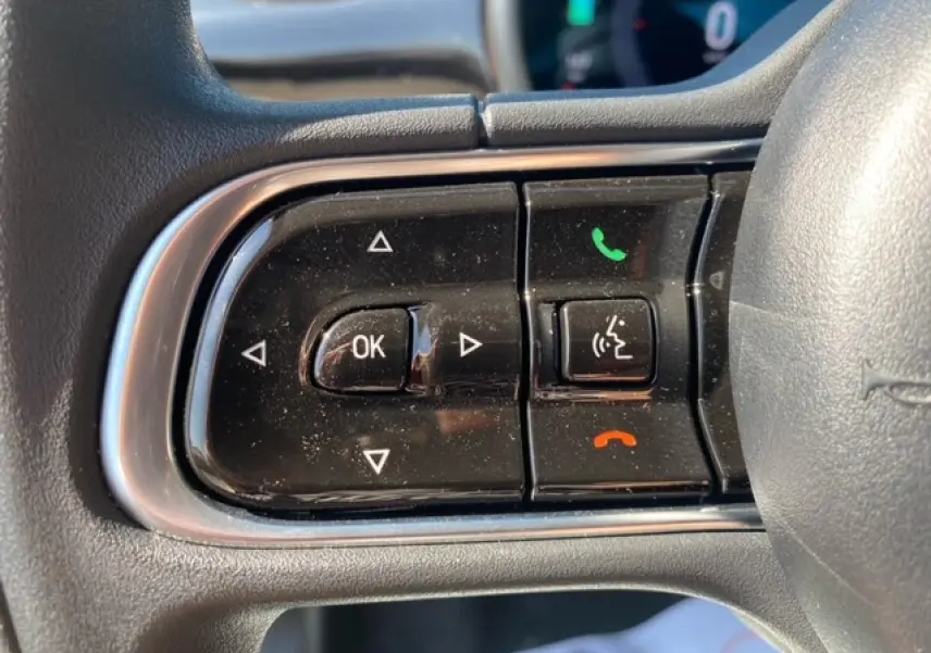 Gros plan sur les commandes multifonctions noires à gauche du volant de la Fiat 500 électrique blanche de 2022.