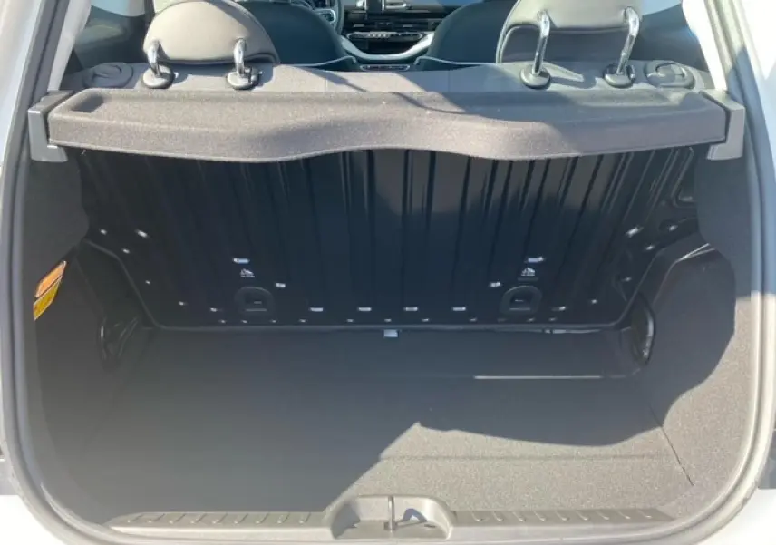 Coffre ouvert vu de l'arrière d'une FIAT 500 électrique blanche, montrant l'espace de chargement et l'intérieur arrière.