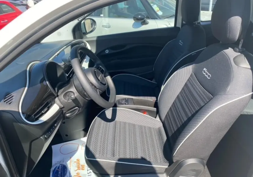 Intérieur avant droit de la Fiat 500 électrique blanche 2022, sièges noirs avec logo 500 brodé et tableau de bord moderne.