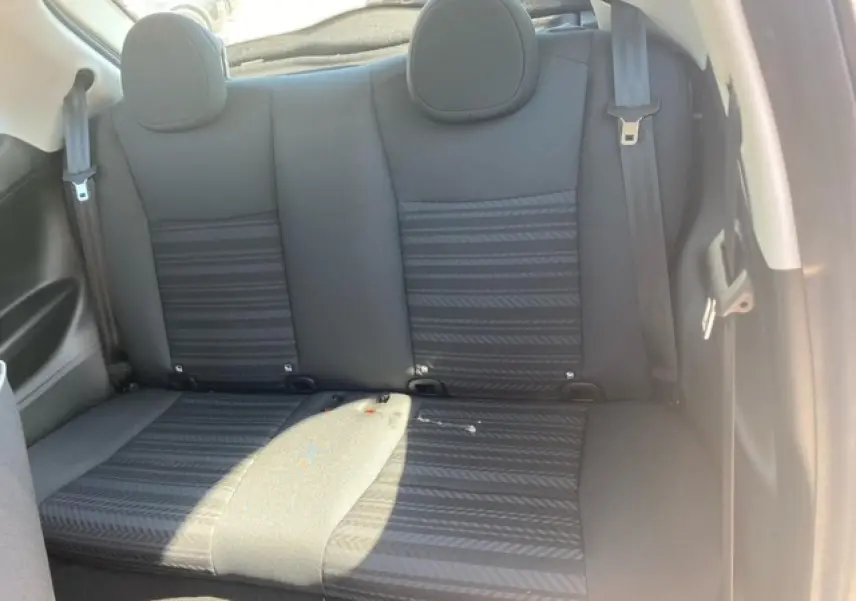 Vue intérieure arrière des sièges noirs de la Fiat 500 électrique blanche, montrant les appuie-têtes et ceintures de sécurité.