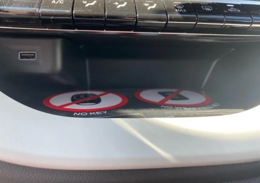Vue rapprochée du compartiment de rangement intérieur blanc de la Fiat 500 électrique avec boutons de commande au-dessus.