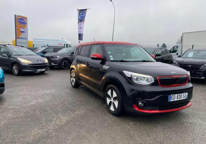 KIA Soul électrique noir avec toit rouge, vue 3/4 avant droit, détails rouges sur calandre et pare-chocs.