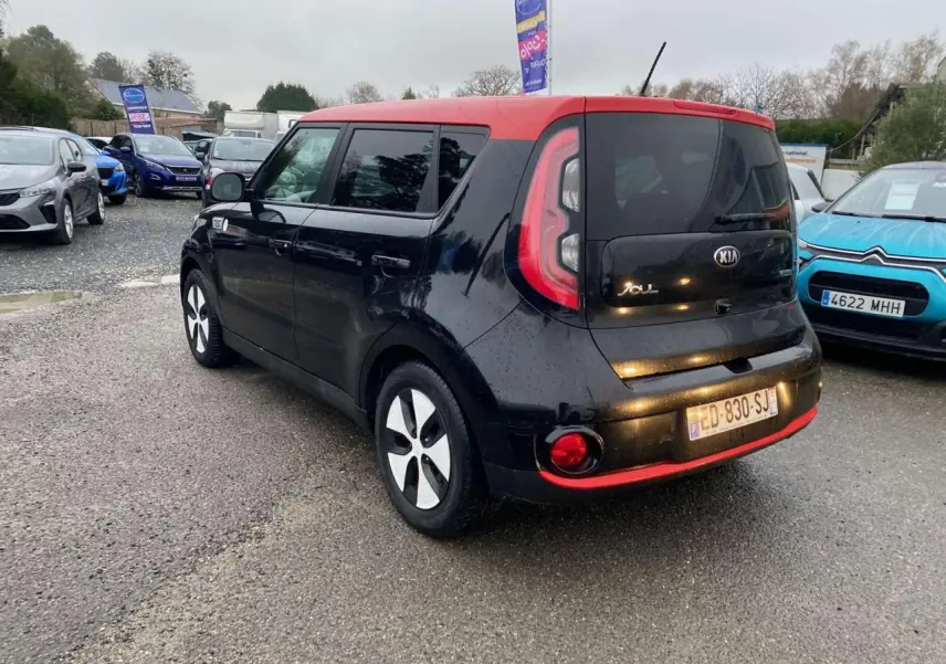 Vue 3/4 arrière droite d'une Kia Soul électrique noire avec toit rouge et jantes alliage 16 pouces.