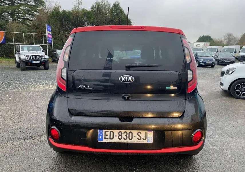 Vue arrière d'une KIA Soul électrique noire avec toit rouge et caméra de recul visible sur le hayon.