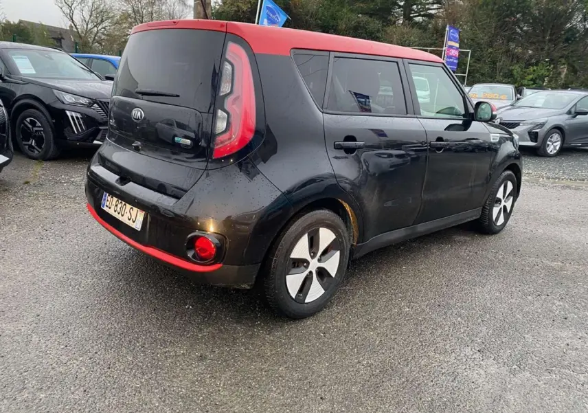 Vue 3/4 arrière droite d'une KIA Soul électrique noire avec toit rouge et jantes alliage 16 pouces.