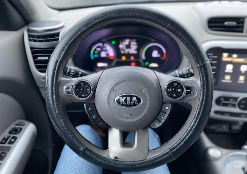 Vue intérieure centrée sur le volant KIA d'un Soul électrique 2016, avec tableau de bord et commandes visibles.