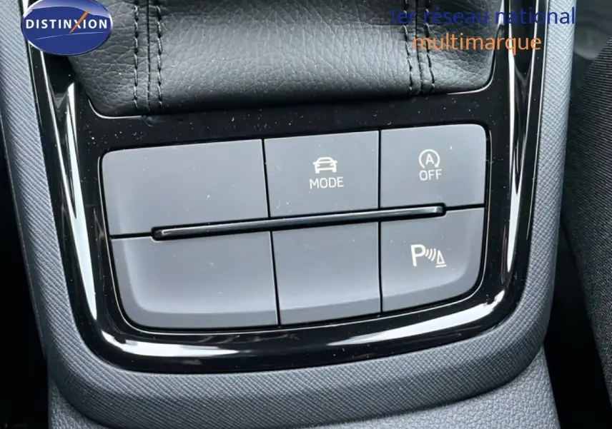 Gros plan sur les commandes de mode de conduite et assistance au stationnement du Skoda Kamiq gris graphite, intérieur tissu noir.