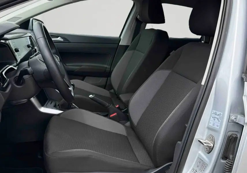 Vue intérieure côté conducteur de la Volkswagen Polo 2025 gris, montrant sièges tissu noirs et tableau de bord moderne.